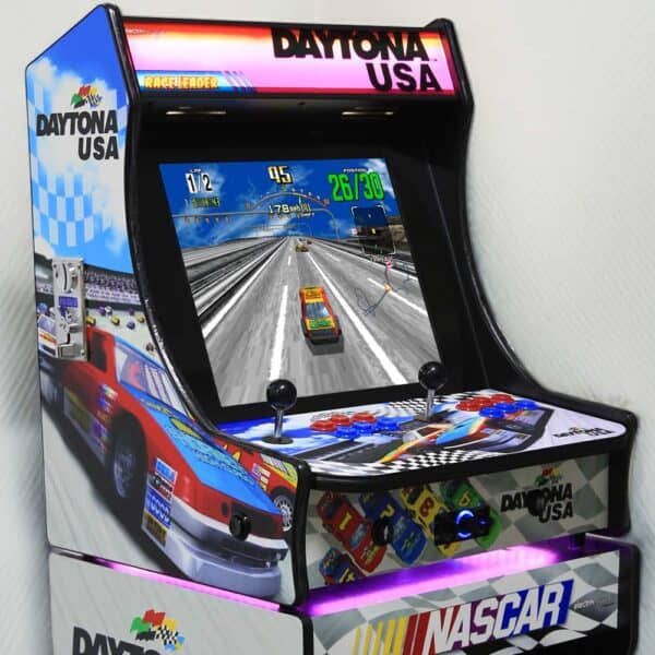 Daytona USA arcade racing game with steering wheel and pedals.
