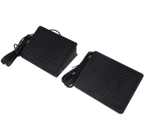 Two black foot pedals for arcade gaming with textured surfaces and attached cables.